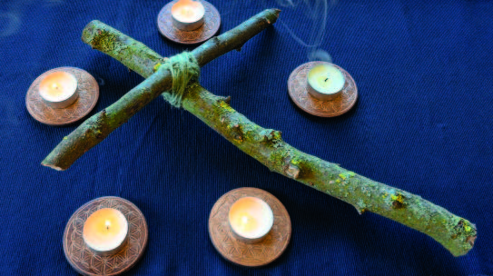 Teelichter um ein Kreuz aus Zweigen